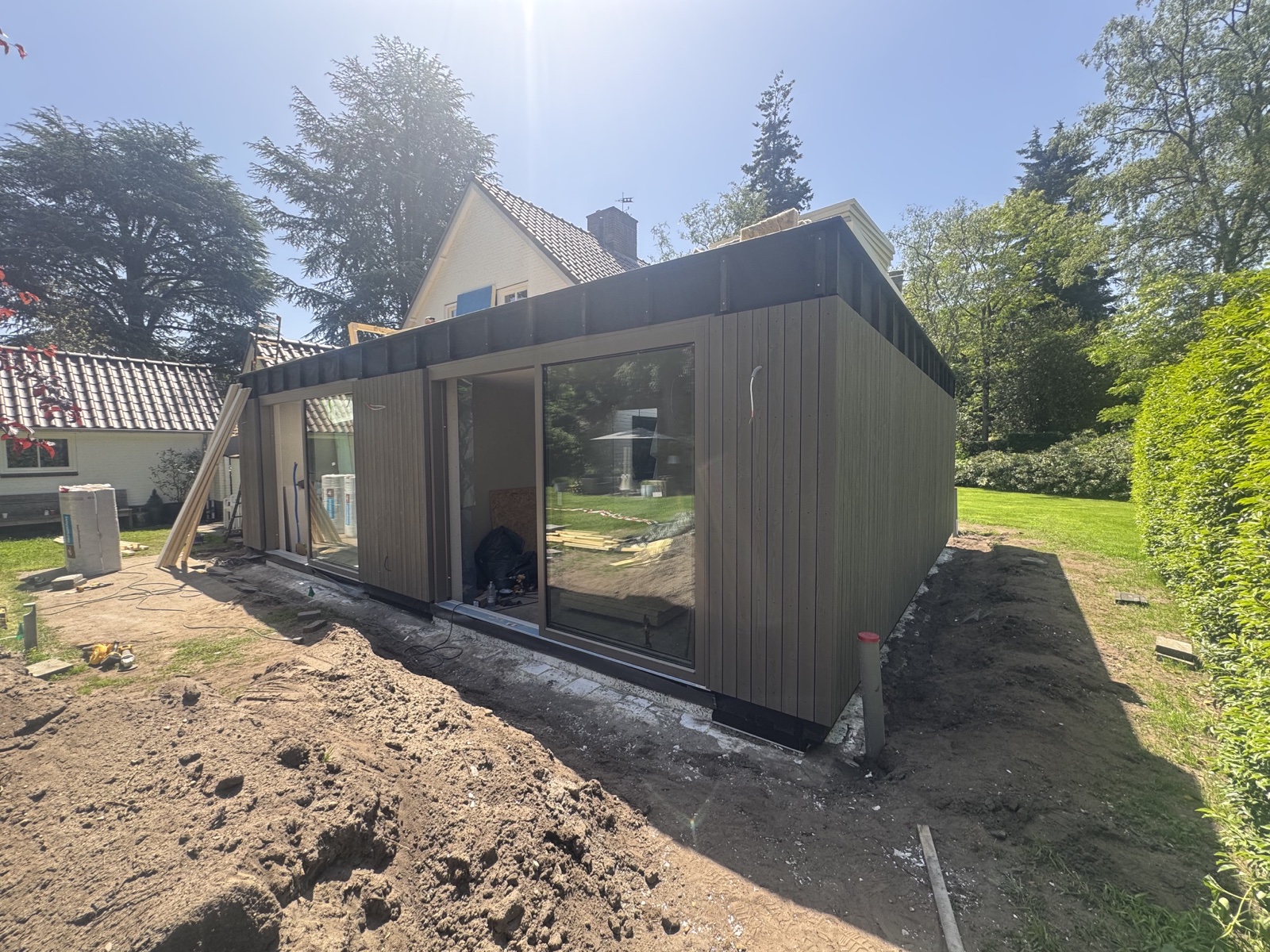 Moderne aanbouw met houten gevelbekleding en grote glaspartijen